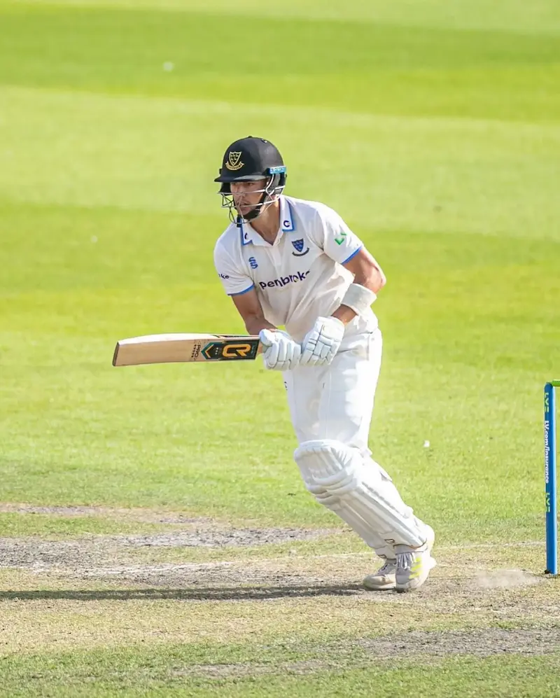 Cricket batsman in white uniform with CR bat playing shot on pitch during match